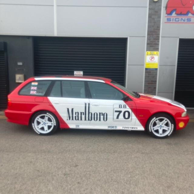 Branded car with custom vehicle wrap parked outside a business.